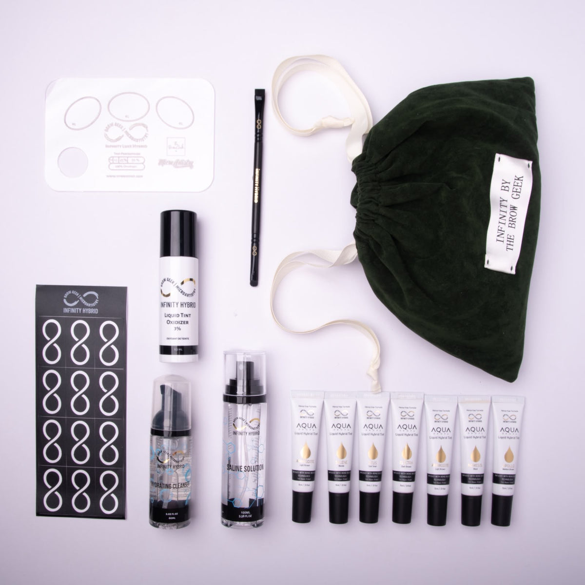 Aqua Drops® Gold Kit flat lay: 7 hybrid brow dye shades, liquid brow tint developer, brow cleanser, saline, stencils, mapping pen and green velvet bag, Infinity by The Brow Geek